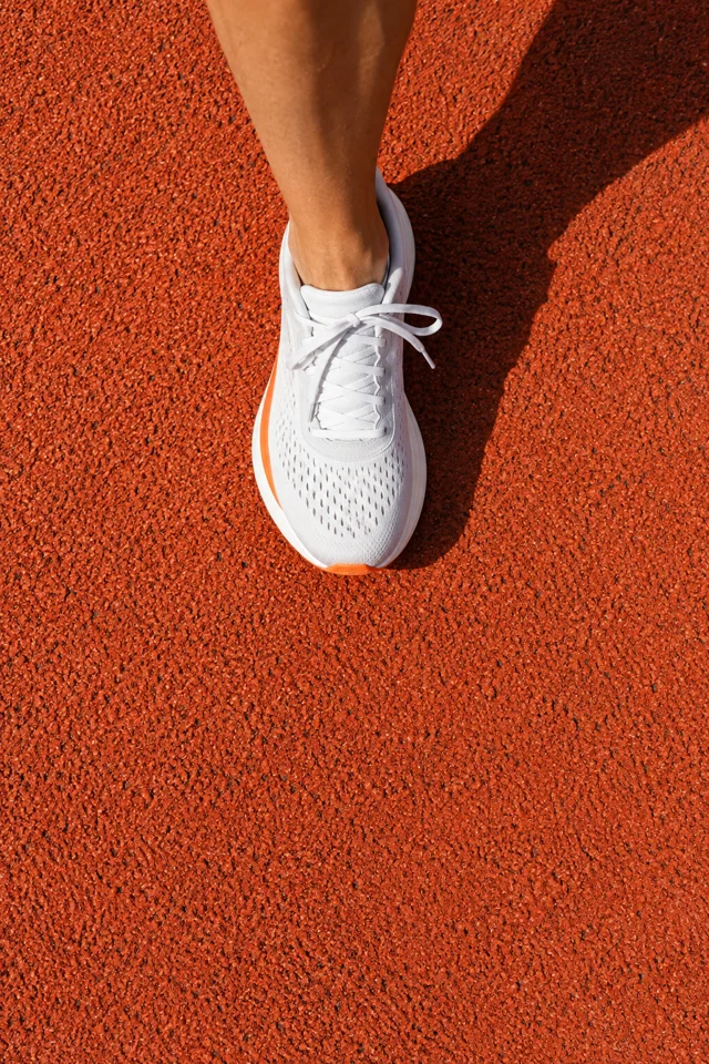 Illustrative white sneaker on an orange running track